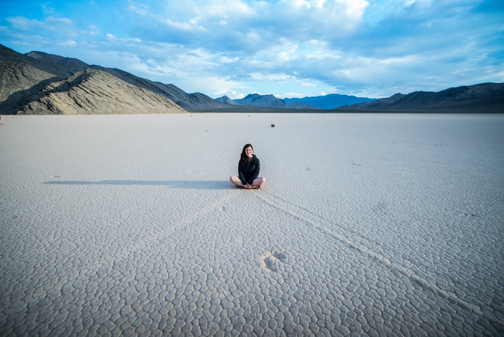 a woman sitting in the middle of a desert