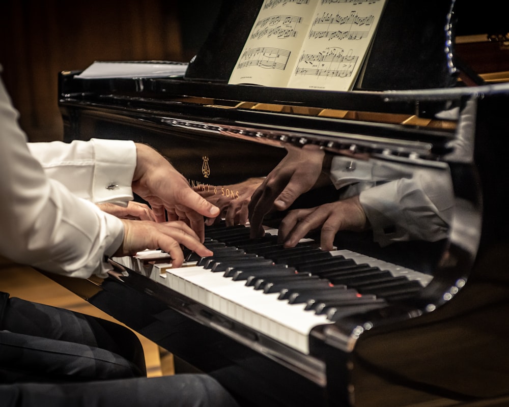 Un par de personas que están sentadas al piano