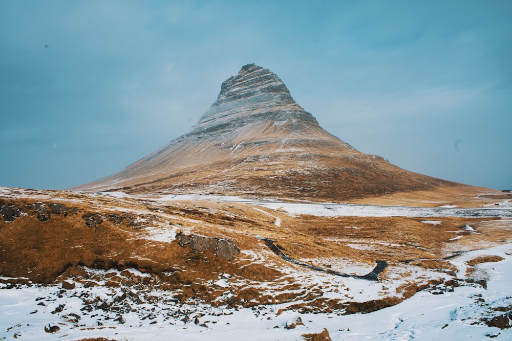 a tall mountain with a snow covered ground