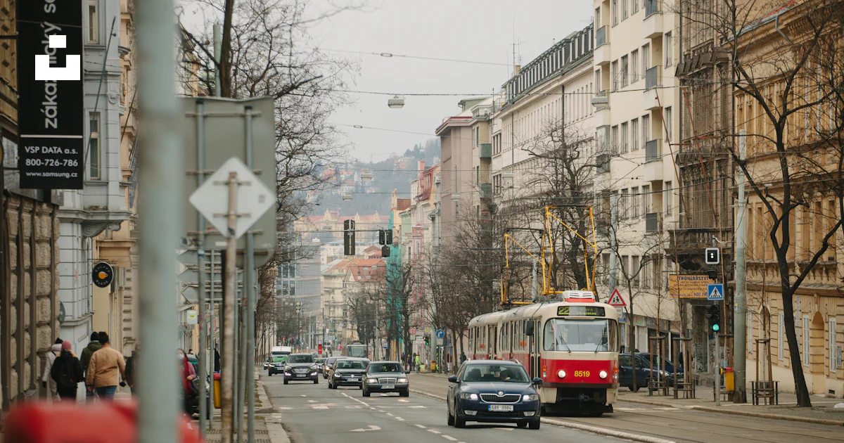 Ein rot-weißer Bus, der eine Straße neben hohen Gebäuden hinunterfährt ...