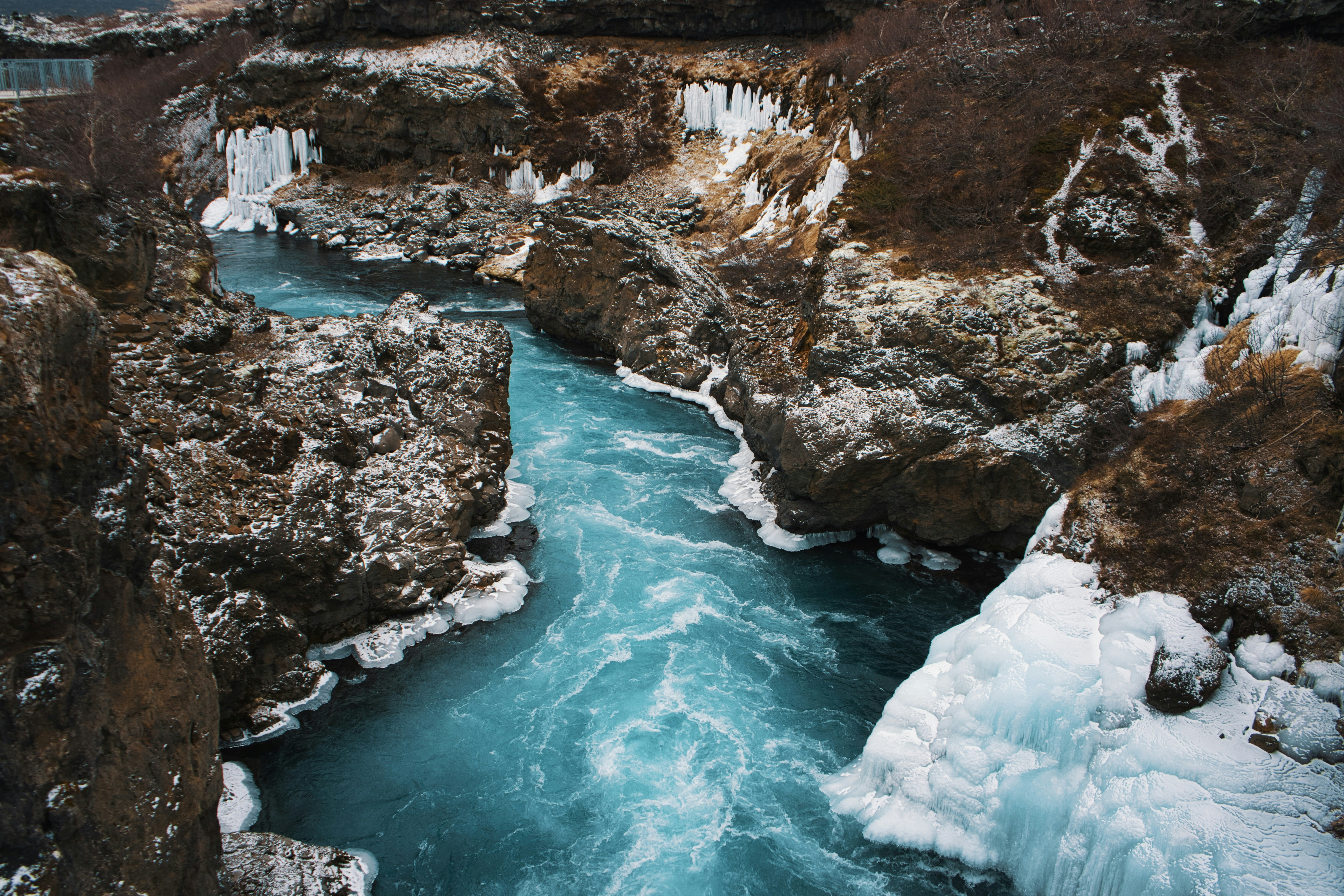 a river flowing through a canyon next to snow covered rocks