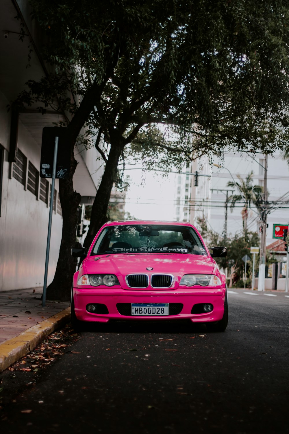 um carro cor-de-rosa estacionado à beira da estrada
