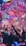 A vibrant indoor event with colorful confetti filling the air. A large crowd of people are gathered, many with raised arms and smartphones capturing the moment. The atmosphere is lively with dynamic lighting casting hues of purple, pink, and blue over the scene.