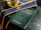 A dark marble table holds a book titled 'Pastoral Care of the Sick' with bilingual text. A purple stole with gold embroidery and a small glass container filled with liquid are placed nearby.