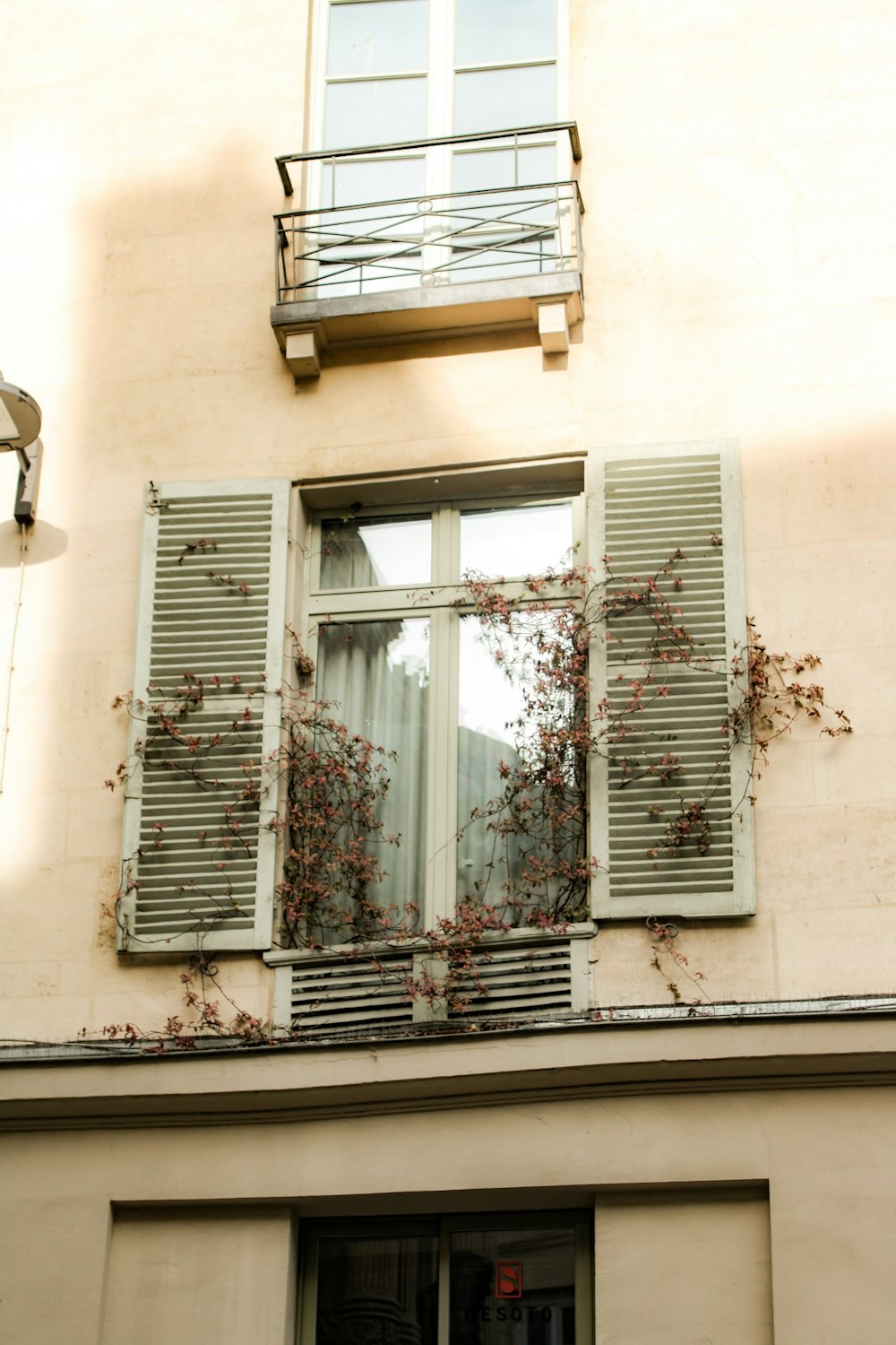 a window with shutters and a balcony above it