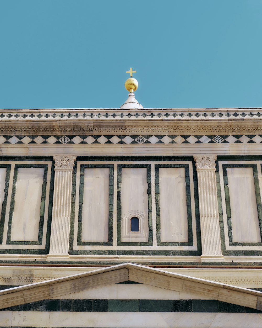 le sommet d’un bâtiment avec une croix dorée sur le dessus