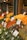 A vibrant market stall displays a wide array of fresh fruits and vegetables, including oranges, bananas, artichokes, carrots, and asparagus. Each produce has a handwritten label with prices attached, enhancing the authenticity and charm of the market setting.