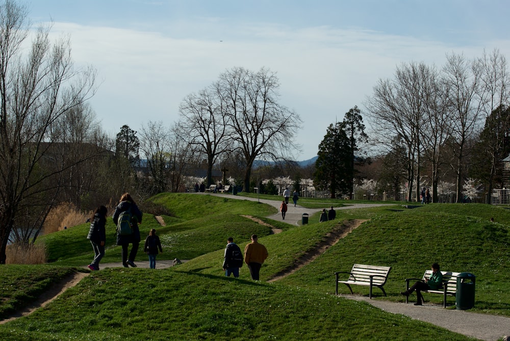 a group of people walking up a hill next to a park