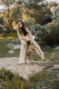 A joyful dog owner playing with their happy dog in a sunlit Nordic forest.