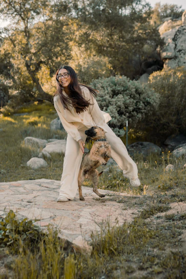 A joyful dog owner playing with their happy dog in a sunlit Nordic forest.