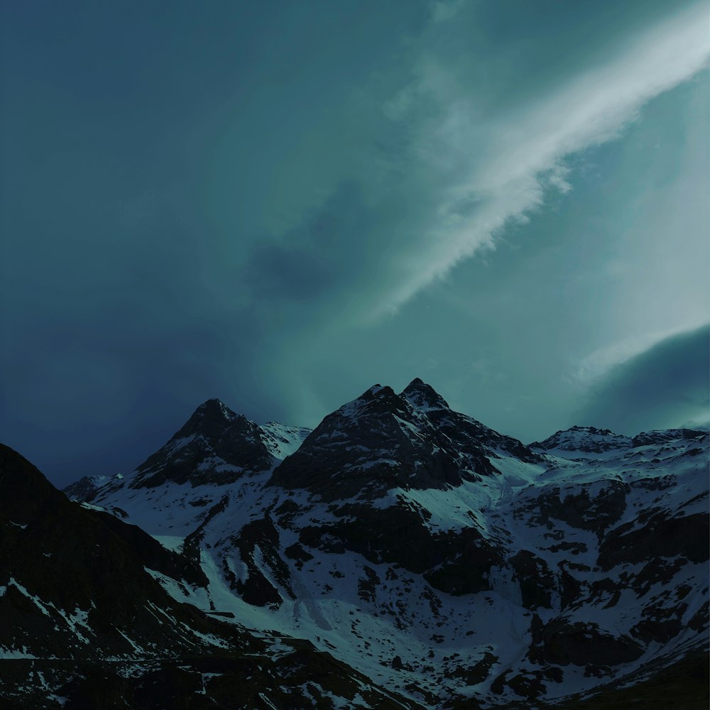 a snowy mountain range under a cloudy sky