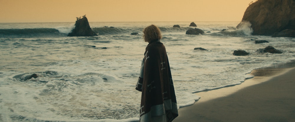 a woman standing on a beach next to the ocean