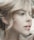 A close-up profile of a person with light hair elegantly styled. The image highlights soft facial features and natural makeup, creating an artistic and serene portrait.