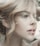 A close-up profile of a person with light hair elegantly styled. The image highlights soft facial features and natural makeup, creating an artistic and serene portrait.