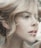 A close-up profile of a person with light hair elegantly styled. The image highlights soft facial features and natural makeup, creating an artistic and serene portrait.