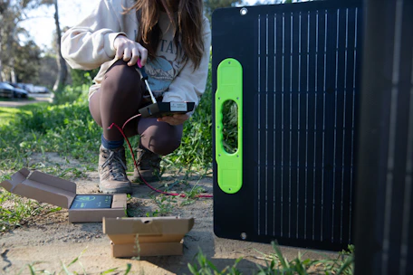 Technician operating geoelectric equipment in a field setting during sunset.
