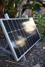 a solar panel sitting on the ground in a garden