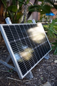 a solar panel sitting on the ground in a garden