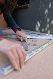 a person using a pair of scissors to cut a piece of metal