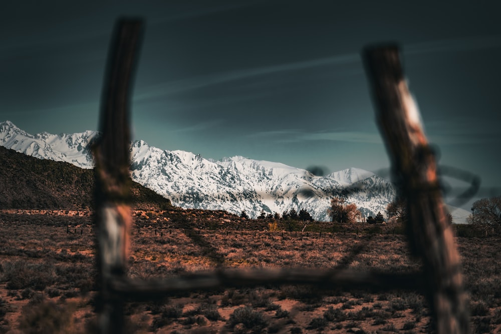 a view of a snowy mountain range through a fence