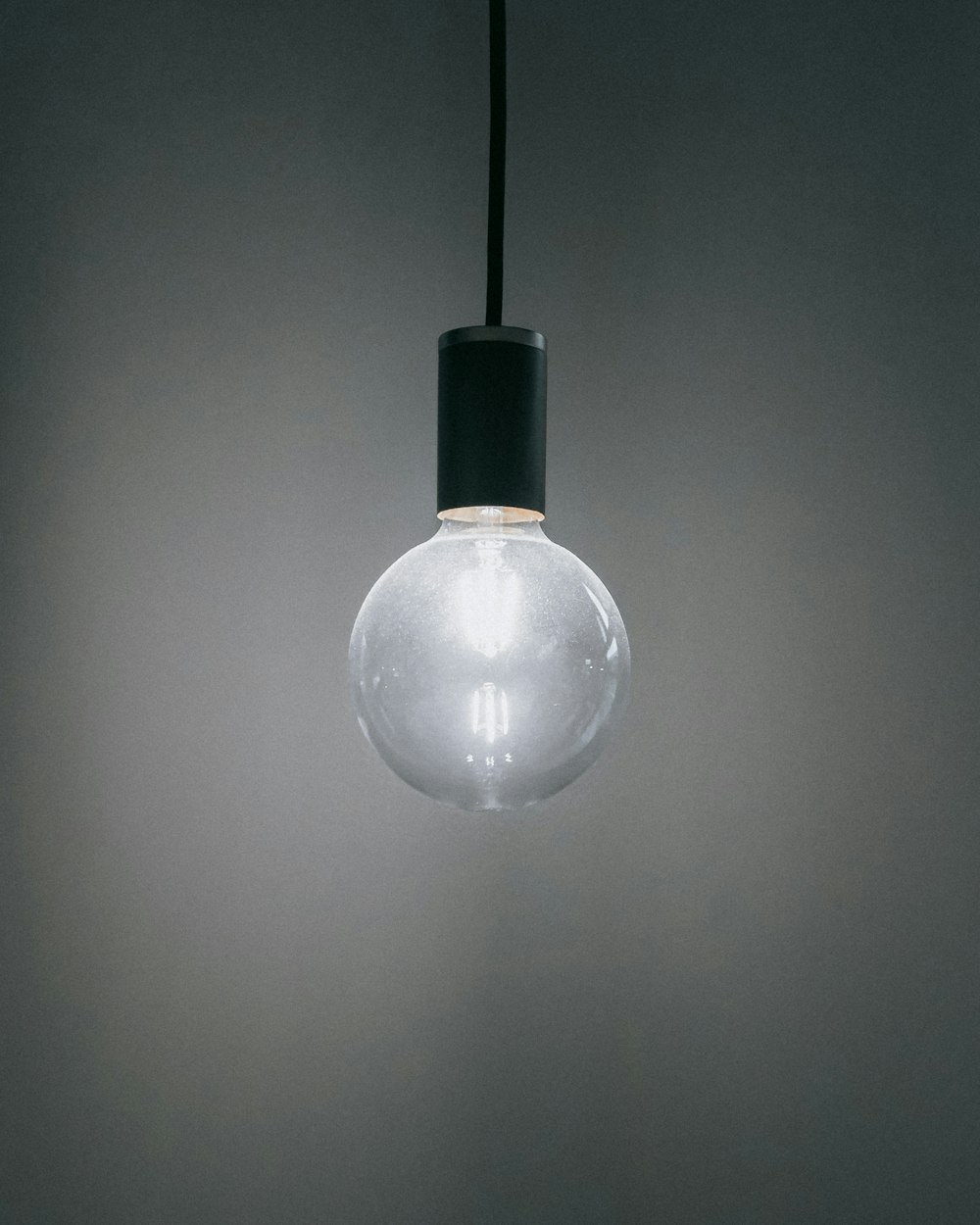 a white light bulb hanging from a black cord