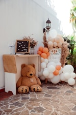 a teddy bear sitting next to a bunch of balloons