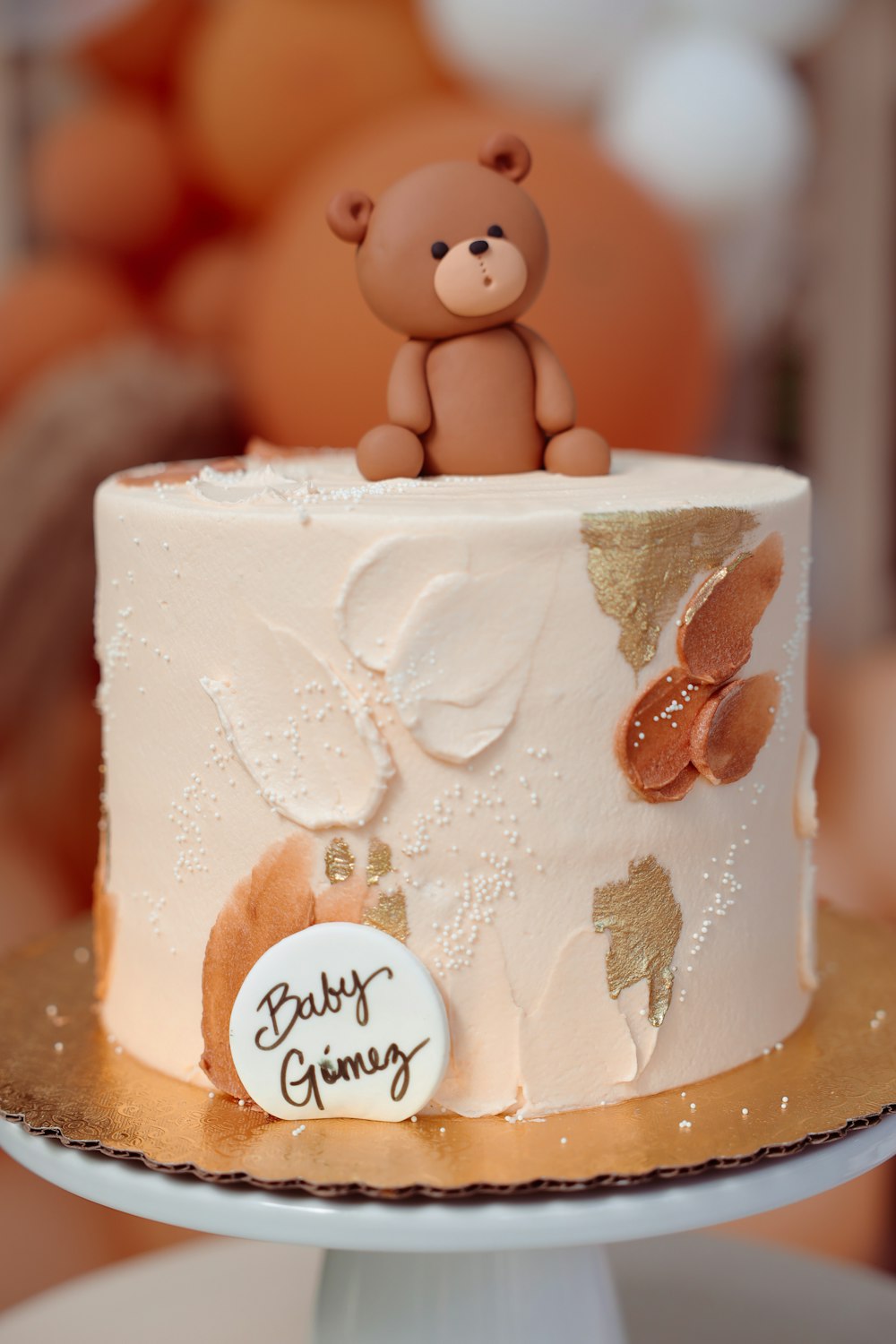 a baby shower cake with a teddy bear on top