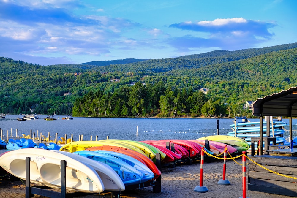 a row of canoes sitting on the shore of a lake