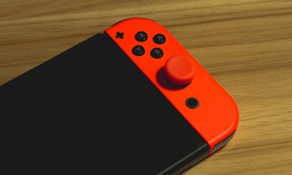 A close-up of a classic retro gaming console with colorful controllers on a wooden table.