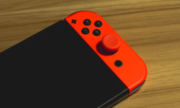 A close-up of a gaming controller on a wooden table.