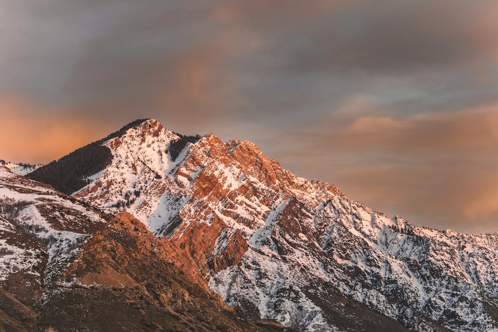 a mountain covered in snow under a cloudy sky