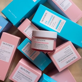 Multiple skincare product boxes and containers with labels featuring Skintific, including a jar labeled MSH Niacinamide Brightening Moisture Gel. The boxes are predominantly pastel blue and pink.