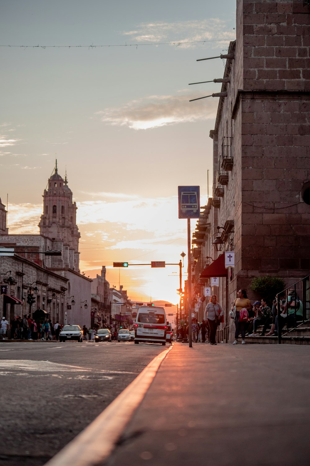 a city street at sunset with cars and people