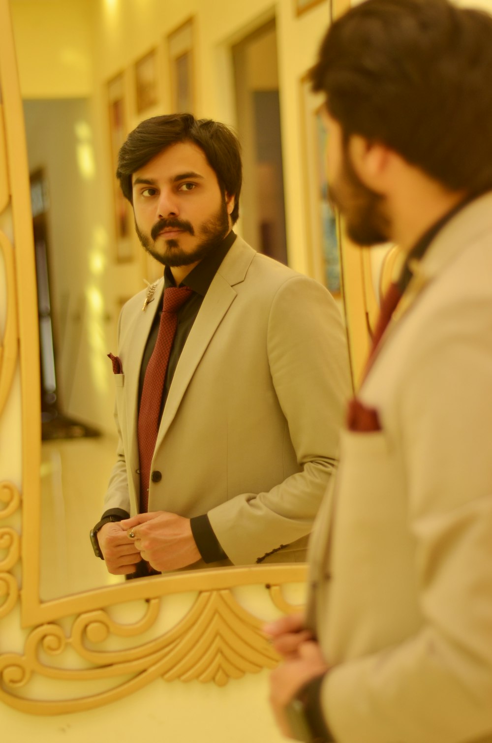 a man in a suit looking at himself in a mirror