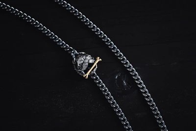 Industrial-style necklace with dark metal chains and a bold pendant on a leather background.