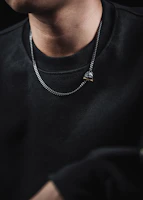 Model wearing a bold chain necklace paired with understated earrings in soft natural light.