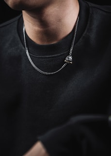 Minimalist chain necklace paired with a casual shirt, photographed outdoors with soft sunlight enhancing textures