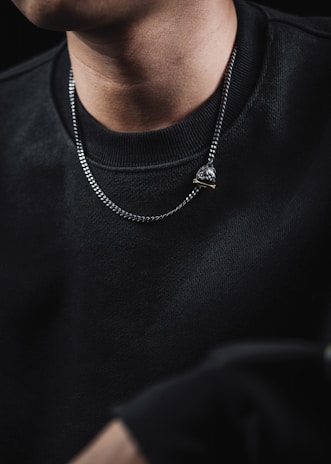 Model wearing a delicate Atalaia necklace illuminated by soft, moody lighting in a dark setting.