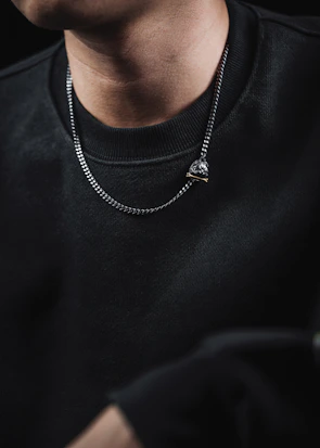 Model wearing a bold chain necklace paired with understated earrings in soft natural light.