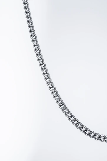 Close-up of a gleaming pure platinum chain resting on a velvet cushion, highlighting its smooth, polished links.
