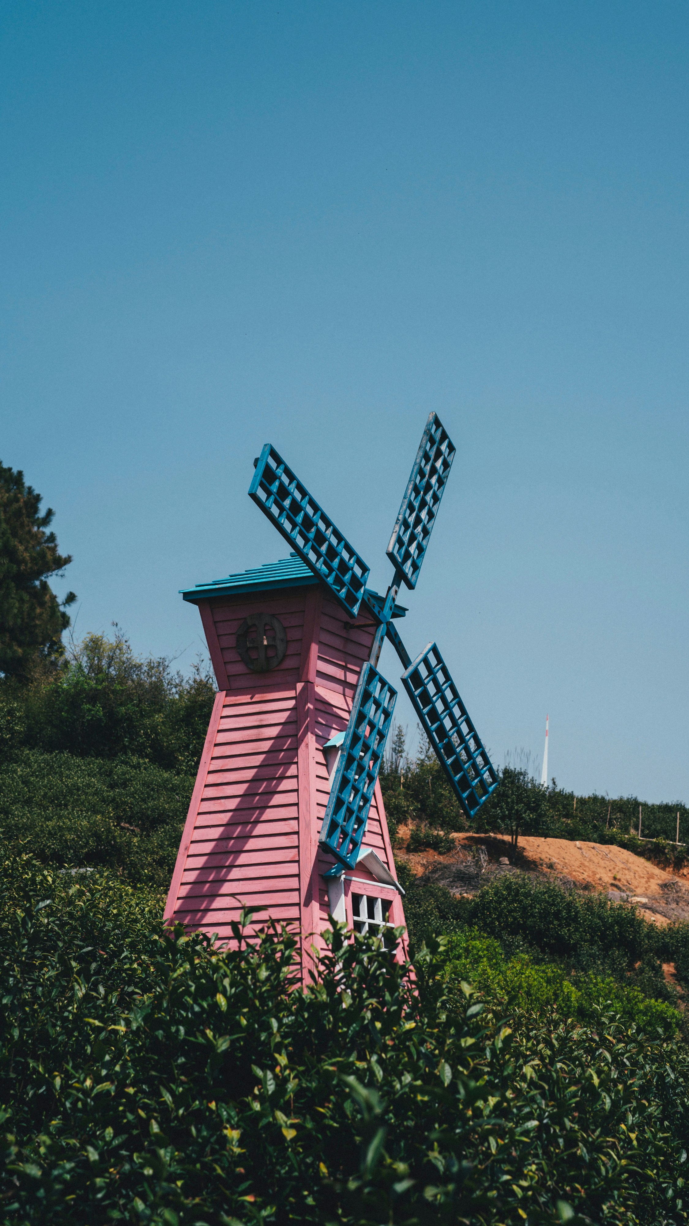 Ein rosafarbenes Gebäude mit einem blauen Dach und einer Windmühle darauf