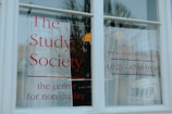 A white window with large, bold red lettering displaying 'The Study Society, the centre for non-duality', along with a web address and phone number.