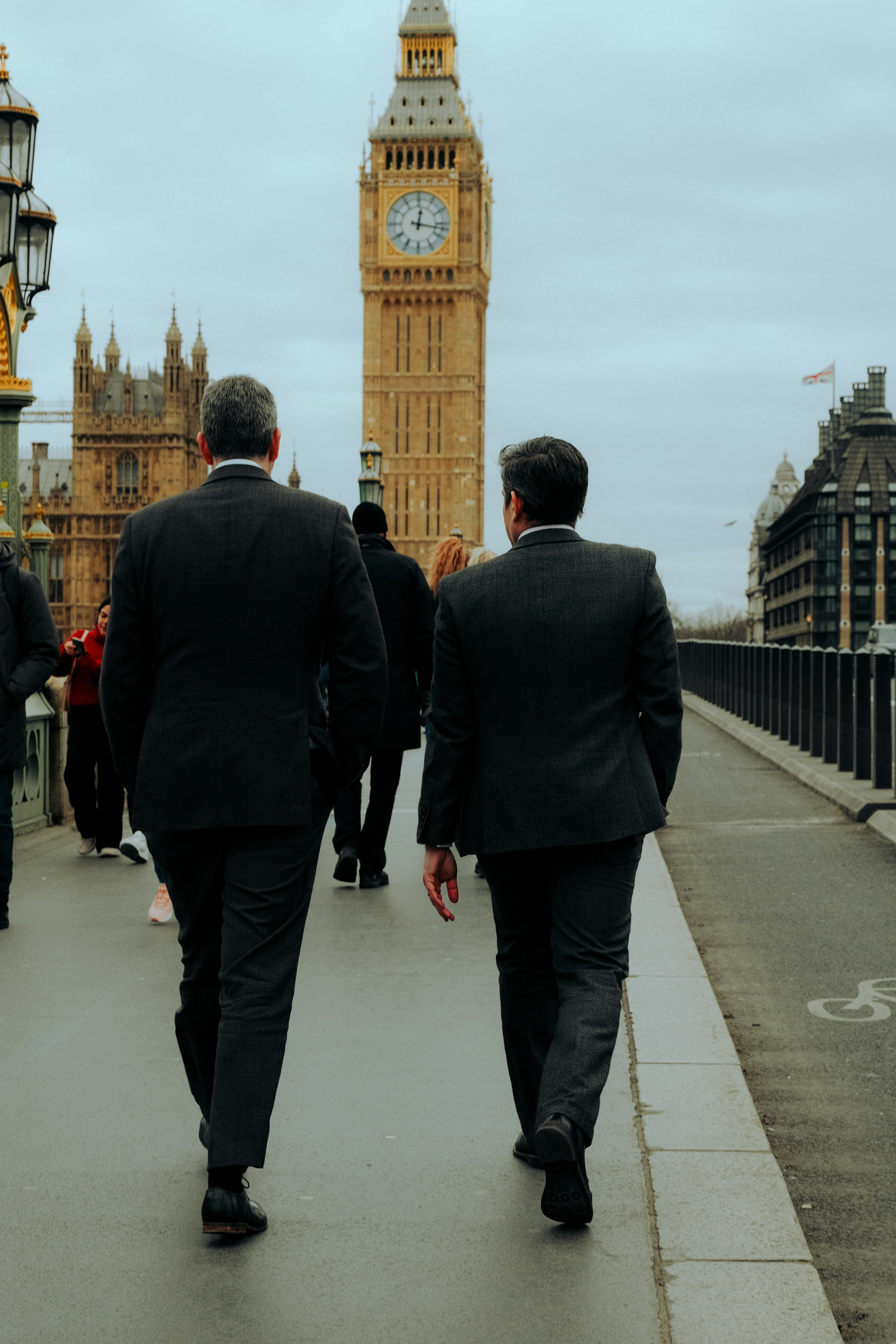 two men in suits walking down a sidewalk