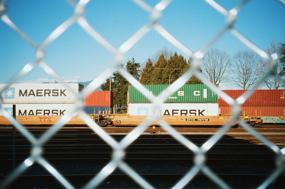 a view through a chain link fence of a freight train