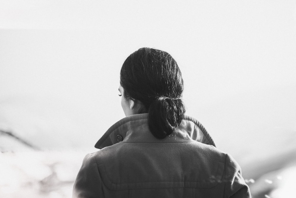 a woman with a ponytail standing in front of a mountain