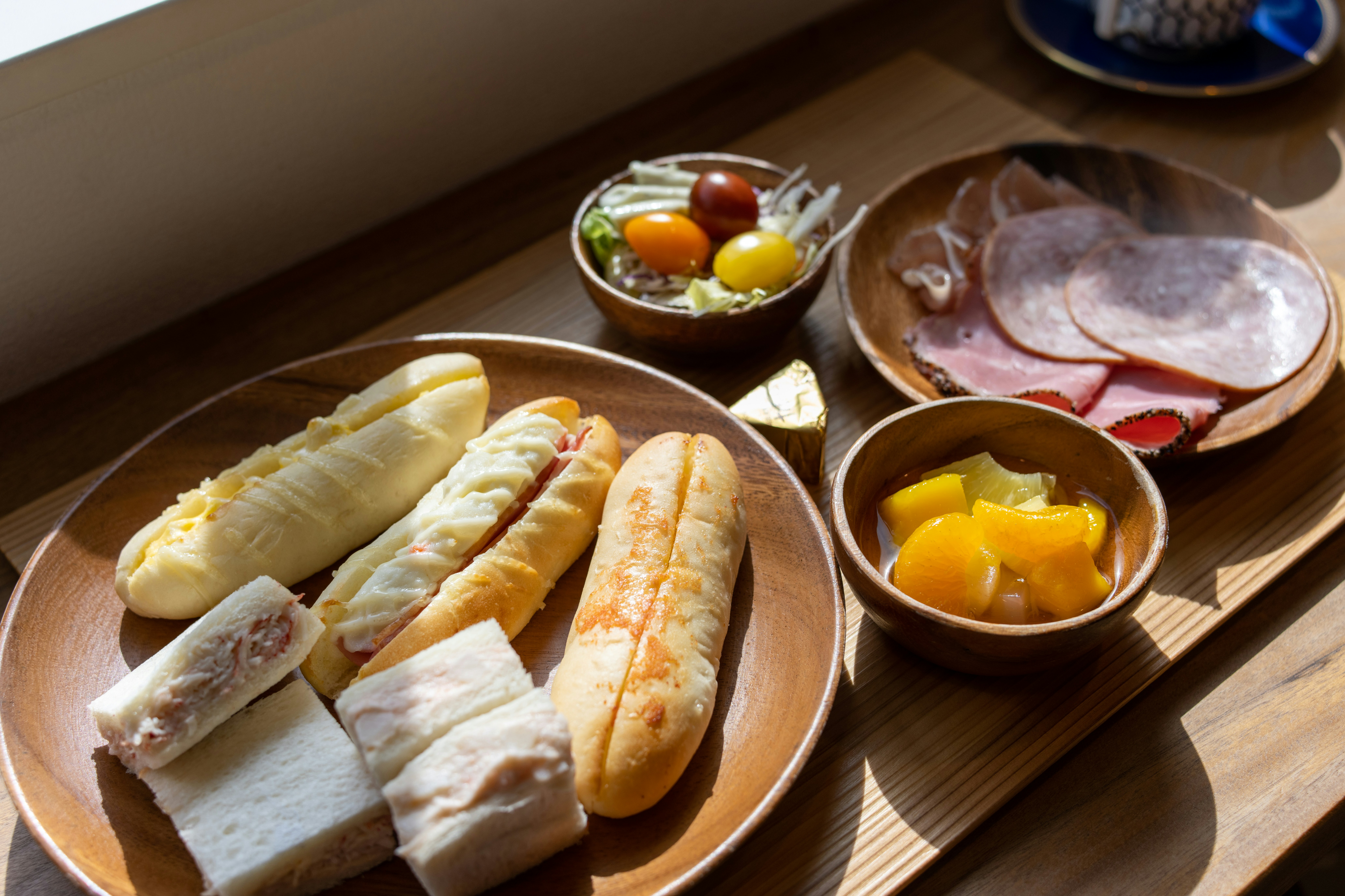 Wooden table of breakfast plates with bread rolls and cheese