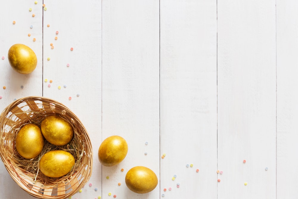 a basket filled with golden eggs on top of a white table