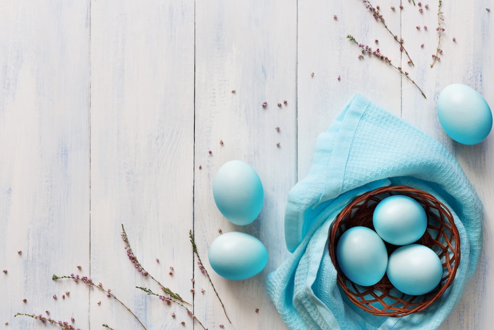 a basket filled with blue eggs on top of a wooden table