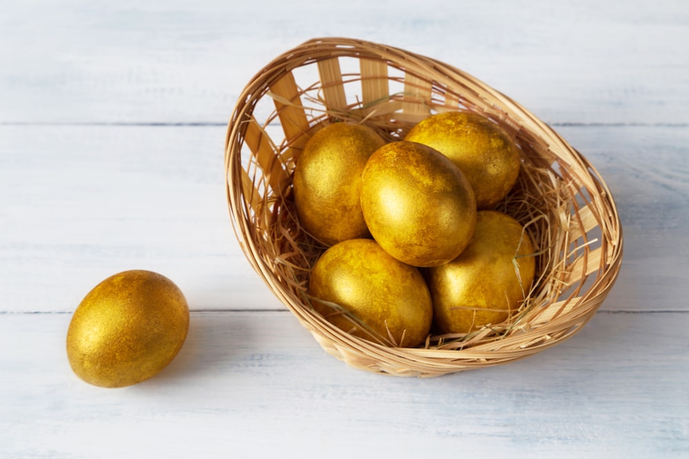 a basket filled with golden eggs on top of a white table