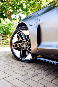 Glossy, freshly detailed car with shining rims and polished paint on a driveway.